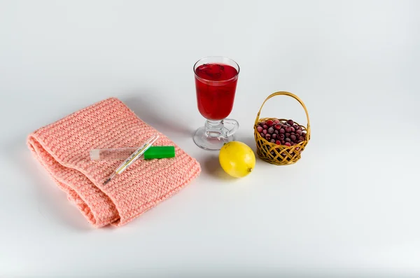 Cachecol quente, um termômetro, limão e suco de oxicoco em um fundo branco — Fotografia de Stock