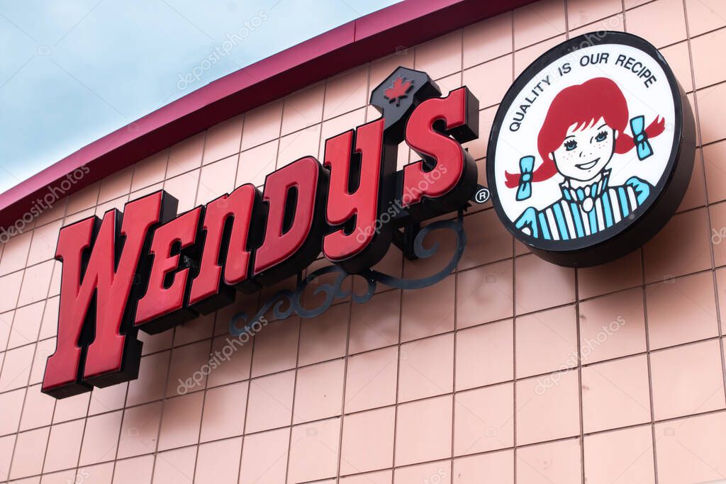 London Ontario, Canada - February 15 2021: Wendy's Canada franchise on a blue winter morning, shot from street view with the Canadian maple leaf substituting the usual apostrophe.