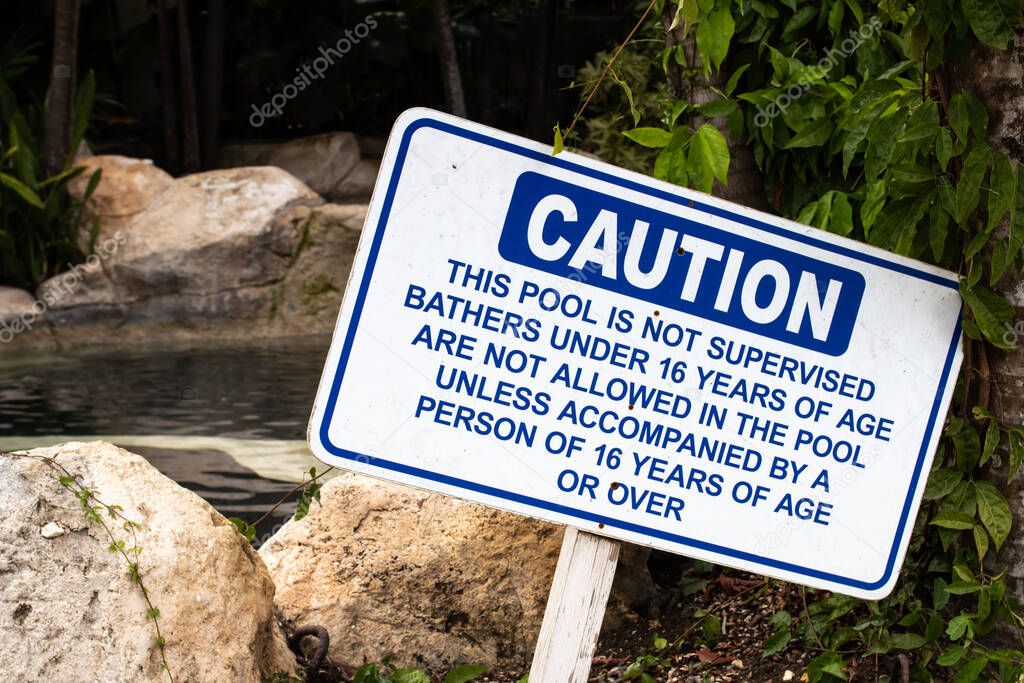 Caution sign that warns hotel patrons that the pool is not supervised, bathers 16 or younger shouldn't enter the pool without an adult accompanying them. Bridgetown, Barbados, 2021.