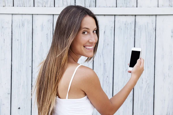 Smiling young woman holding mobile phone — Stock Photo, Image