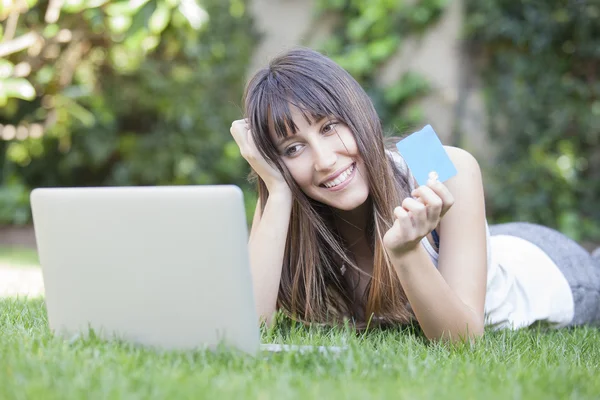 Chica sonriente comprando en línea con un ordenador portátil y tarjeta de crédito — Foto de Stock