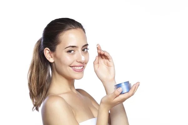 Retrato de una hermosa mujer rubia aplicando un poco de crema facial en su nariz aislada sobre fondo blanco — Foto de Stock