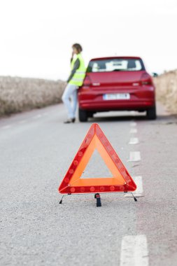 Kadın kırmızı bir arabanın yanında duran bir servise sesleniyor.