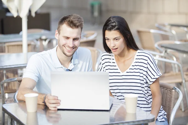 Pareja feliz viendo las redes sociales en un portátil en la terraza de un restaurante — Foto de Stock