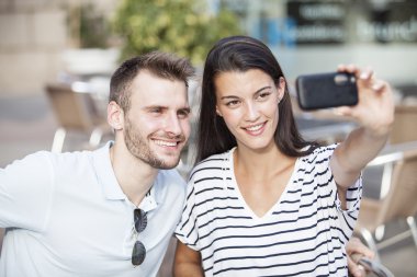 Mutlu çifte bir restoranın terasında bir akıllı telefon ile selfie fotoğraf çekme
