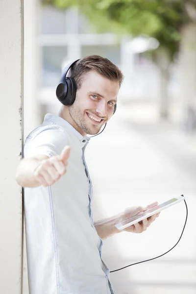 Щасливий хлопець ходить і використовує смартфон, щоб слухати музику з навушниками — стокове фото