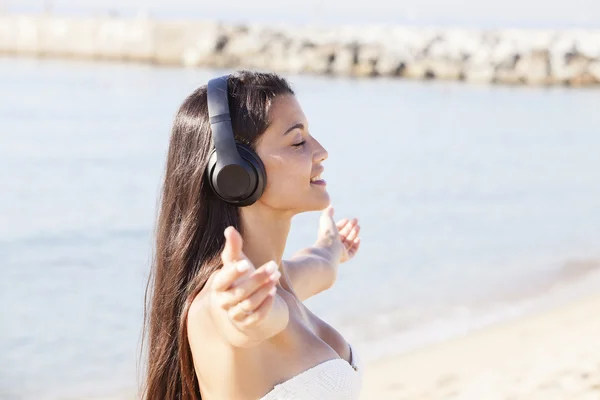 Woman listening to music with headphones at beach — Stock Photo, Image