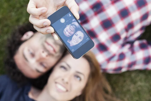 Coppia che si rilassa nel parco facendo selfie in una giornata di sole — Foto Stock