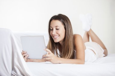 güzel gülümseyen kadın yatakta tablet bilgisayar kullanarak