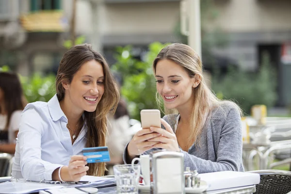 Teman membeli online dengan telepon dan kartu kredit di teras bar — Stok Foto