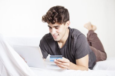 Dijital tablet ve kredi kartı ile online alışveriş yaparken rahat genç adam