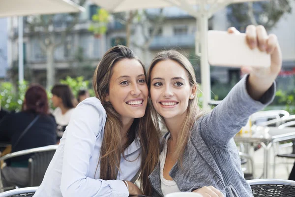 Two happy, beautiful girlfriends taking selfie photo with cellphone — Stock Photo, Image