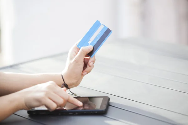 Close-up woman's hands holding a credit card and using digital tablet