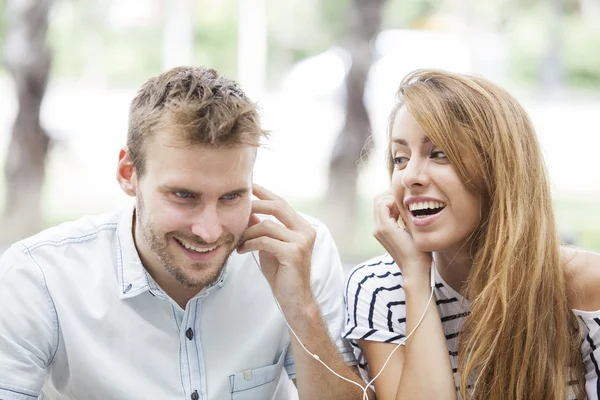 Smiling young couple listening to music together — Stock Photo, Image