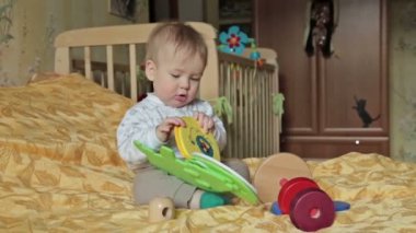 Erkek yatakta oturmuş oyuncakla oynarken mutlu bebek