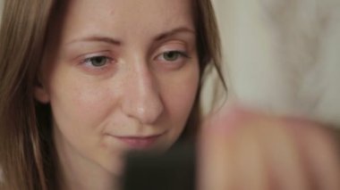 Evde cep telefonu kullanan genç bir kadın.