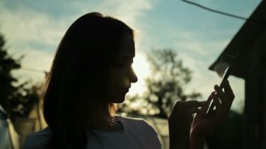 gün batımında akıllı telefon olan kadın silüeti