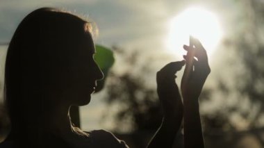 gün batımında akıllı telefon olan kadın silüeti