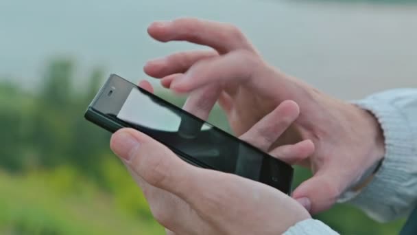 Fermer les mains de la femme à l'aide d'un téléphone à écran tactile à l'extérieur