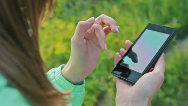 Fermer les mains de la femme à l'aide d'un téléphone à écran tactile à l'extérieur