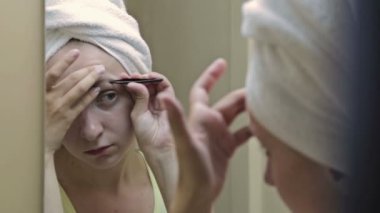 Güzel kadın aynanın önünde kaşlarını koparma