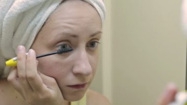 Güzel genç kadın banyoda ayna önünde maskara koymak