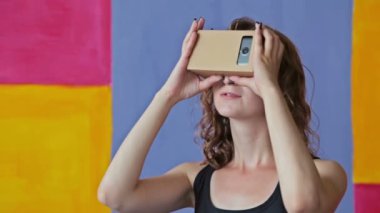 Sanal gerçeklik gözlük kullanan genç kıvırcık kadın. Google karton