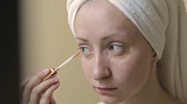 Genç, güzel bir kadın banyoda onu göz kapağı üzerinde uygulanan kapatıcı