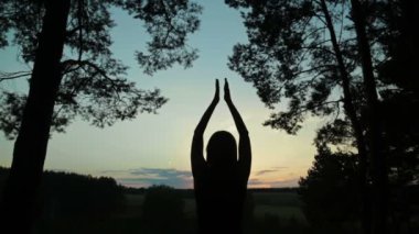 Mutlu genç kadın silueti gökyüzüne karşı ellerini havaya kaldırdı