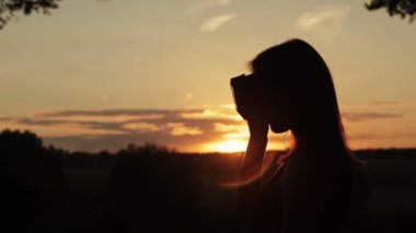 Kadın bir sanal gerçeklik gözlük ormanda günbatımında kullanır