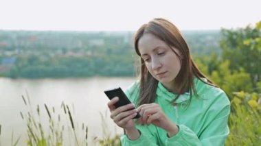 Güzel kız nehrin telefon ile dolgu üzerinde ayakta