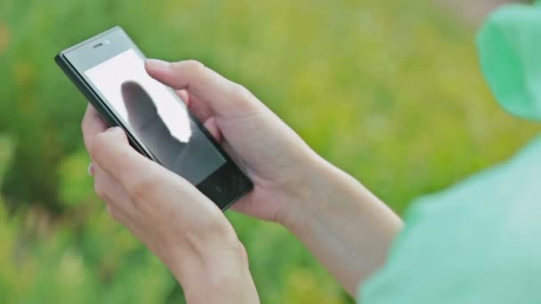 Fermer les mains de la femme à l'aide d'un téléphone à écran tactile à l'extérieur