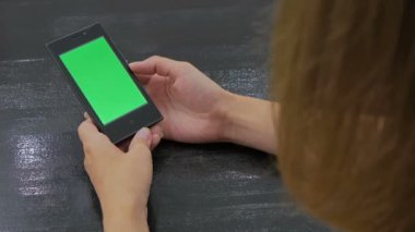 Yeşil ekranlı akıllı telefona bakan kadın