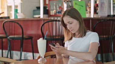 Kafede akıllı telefon kullanan bir kadın.