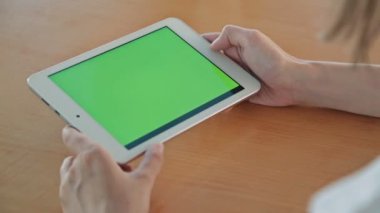 Kafede yeşil ekranlı tablet bilgisayar arayan kadın