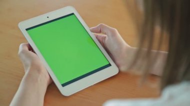 Kafede yeşil ekranlı tablet bilgisayar arayan kadın