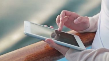 Tablet cruise gemi güvertesinde güneş doğarken kullanan kadın