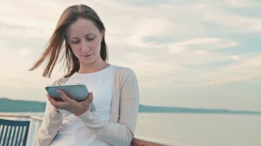 Tablet cruise gemi güvertesinde güneş doğarken kullanan kadın