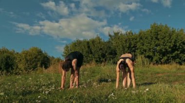 Sportif erkek ve kadın gün batımında parkta Ashtanga yoga yaparken
