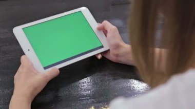 Yeşil ekranlı tablet bilgisayara bakan kadın