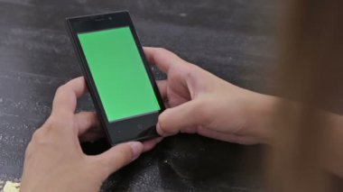 Yeşil ekranlı akıllı telefona bakan kadın