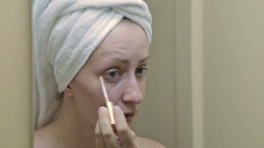 Genç, güzel bir kadın banyoda onu göz kapağı üzerinde uygulanan kapatıcı