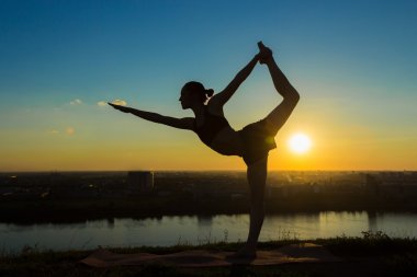 Gün batımında - dans poz efendisi pratik Yoga parkta kadın
