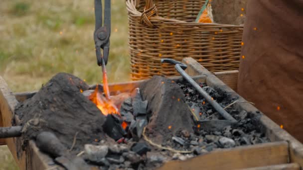 Blacksmith heating metal piece in outdoor forge at medival festival - close up — Stock Video