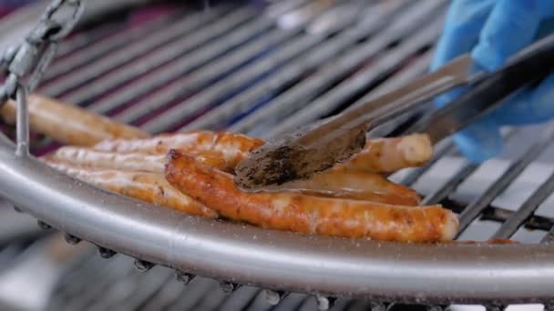 Slow motion: chef grilling fresh meat sausages on big round hanging grill — Stock Video