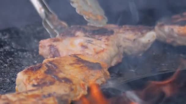 Chef with tongs grilling meat steaks on brazier: close up, slow motion — Stock Video
