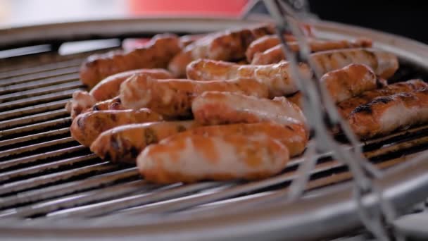 Slow motion: chef grilling fresh meat sausages on big round hanging grill — Stock Video