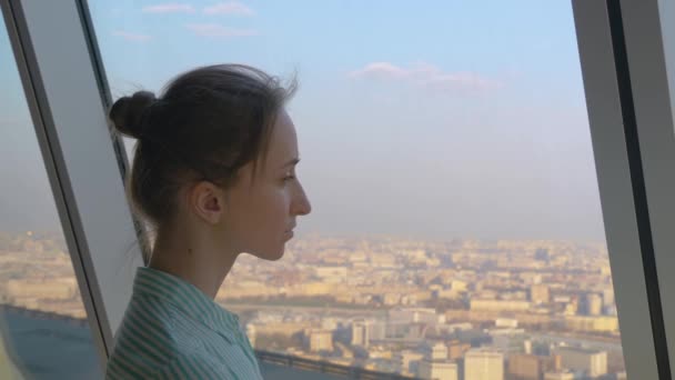 Retrato de mujer mirando el paisaje urbano a través de la ventana del rascacielos — Vídeos de Stock