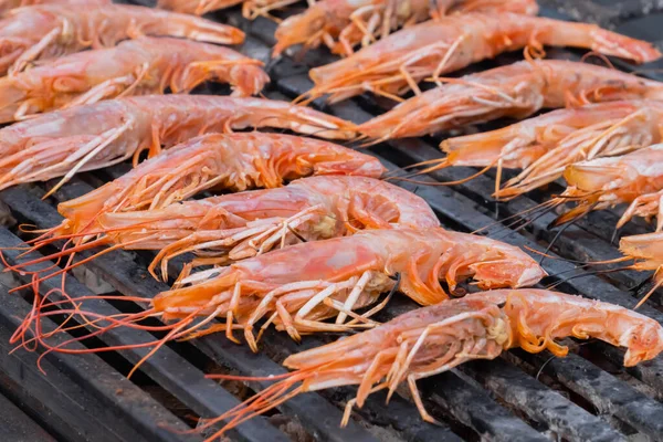 Process of cooking fresh red langoustine shrimps, prawns on grill - street food