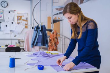 Terzi, tasarımcı dikiş atölyesinde kumaş ölçümü yapıyor.